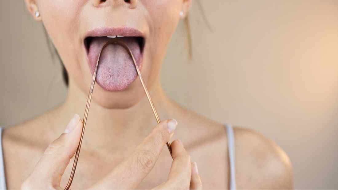 vrouw schraapt haar tong voor het tandenpoetsen